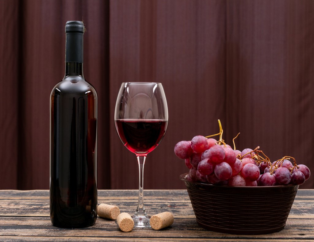 side-view-red-wine-bottle-glass-grape-dark-table-horizontal.jpg